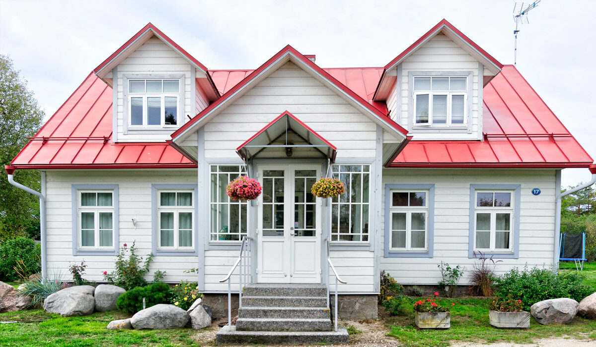 Charming white house with red roof and hanging flower baskets.