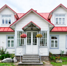 Charming white house with red roof and hanging flower baskets.