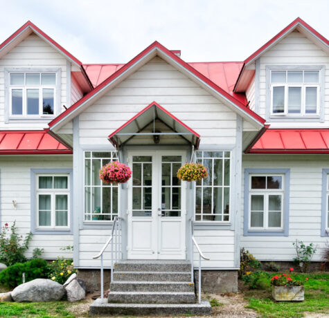 Charming white house with red roof and hanging flower baskets.