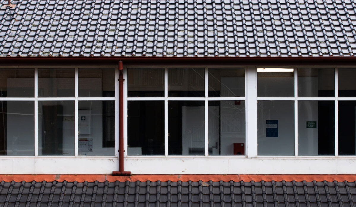 Close-up of a tiled roof and white-framed windows on a building.