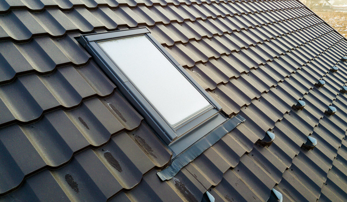 Skylight window installed on a dark tiled roof.