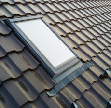 Skylight window installed on a dark tiled roof.