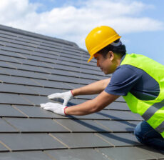 Construction worker installing roof tiles while wearing safety gear.