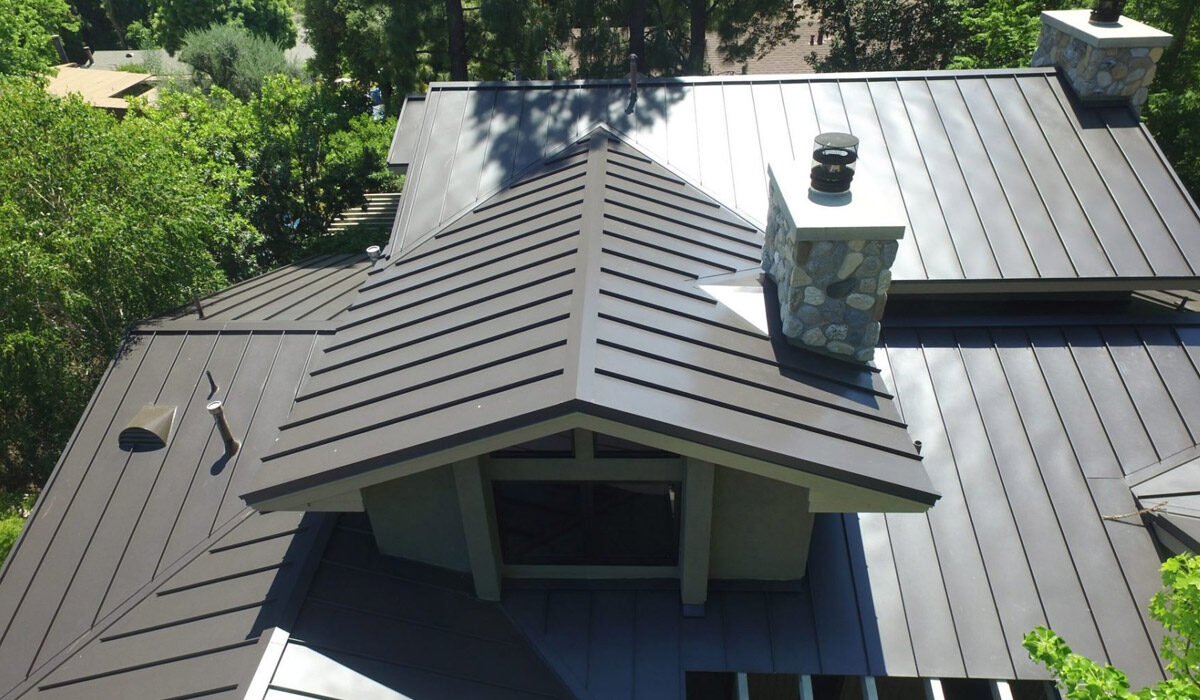 A close-up of a modern metal roof with a chimney during daytime.