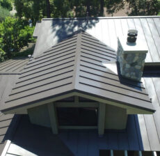 A close-up of a modern metal roof with a chimney during daytime.