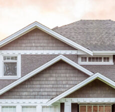 Close-up of a modern house roof with grey shingles under a soft sky.