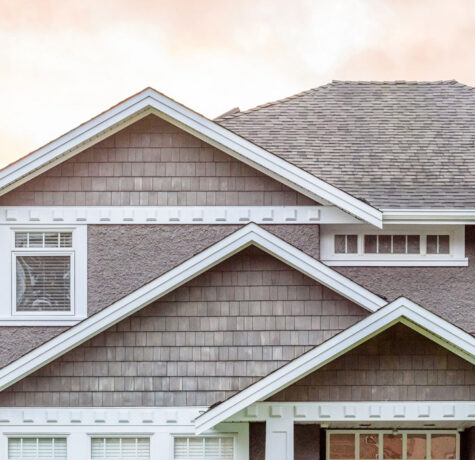 Close-up of a modern house roof with grey shingles under a soft sky.