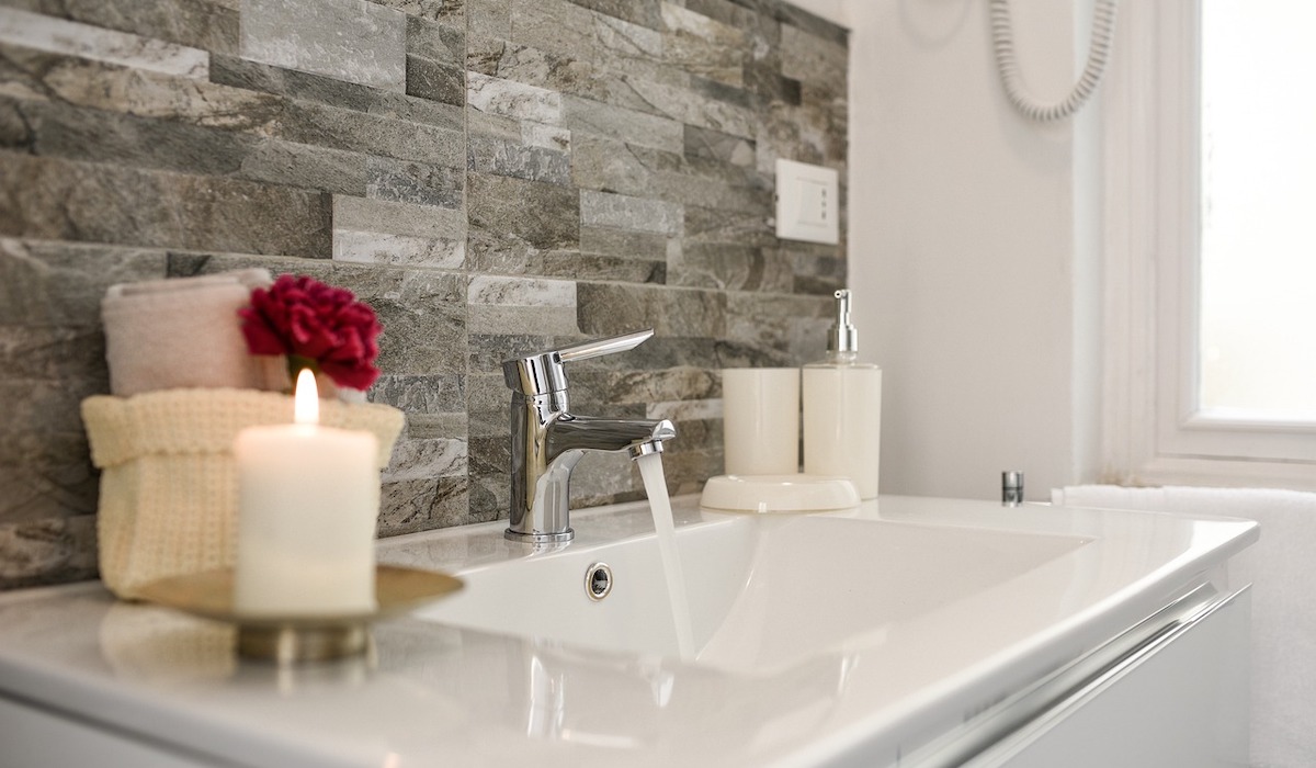 Modern bathroom sink with running water and decorative candles.