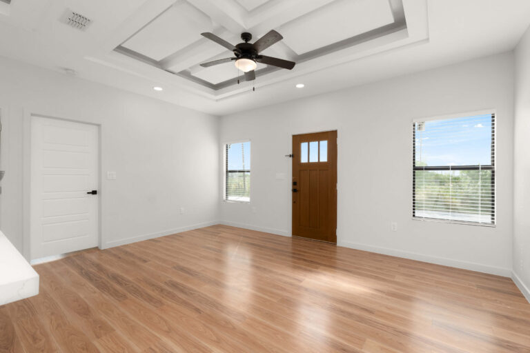 Bright empty room with wooden floor and ceiling fan.