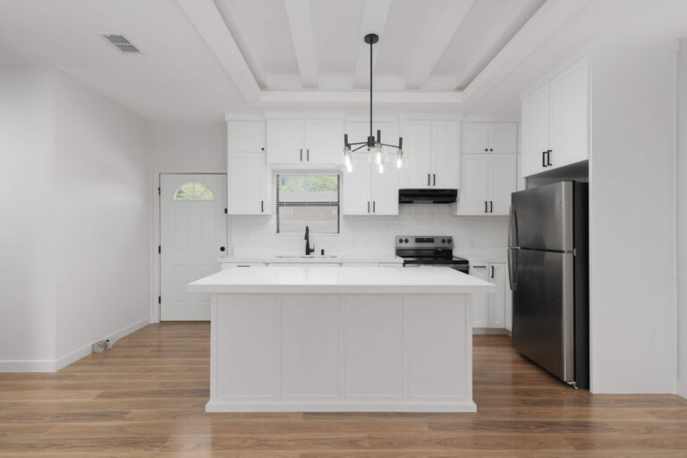Modern white kitchen with island and black appliances.