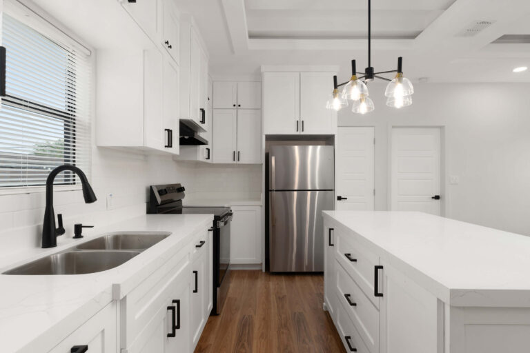 Modern kitchen with white cabinets and stainless steel appliances.