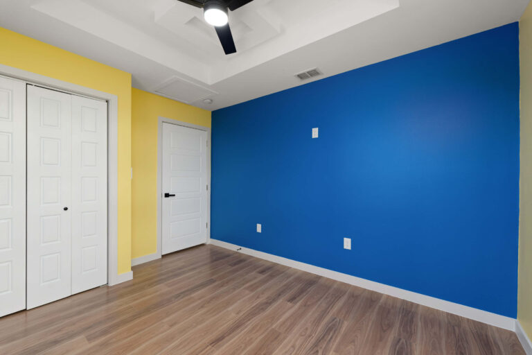 Empty room with blue and yellow walls and wooden flooring.