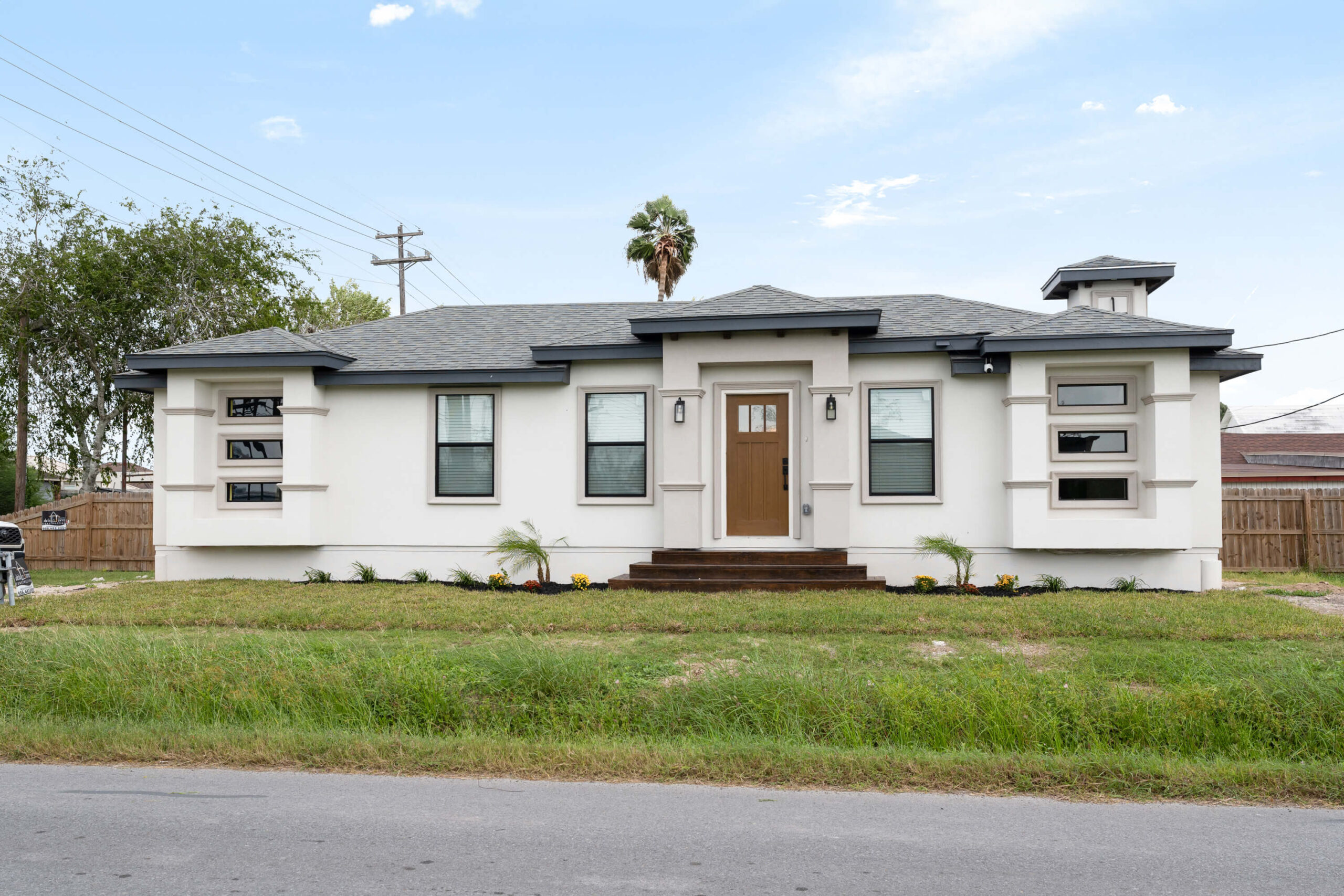 White single-story house with dark roof and wooden front door.